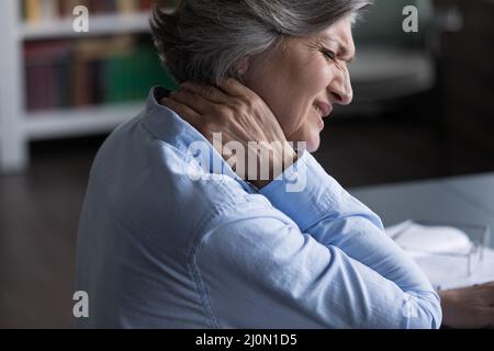 Primo piano donna di mezza età che soffre di dolore al collo Foto Stock