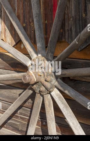 Una vecchia ruota di legno del carro appesa alla parete di un fienile. Foto Stock