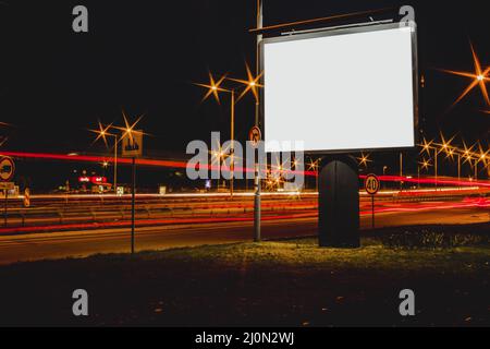 Cartellone pubblicitario vuoto con luci di traffico offuscate notte Foto Stock