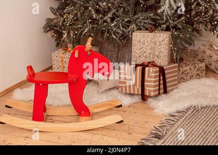 Cavallo rosso dondolante sotto l'albero di Natale festivo con regali Foto Stock