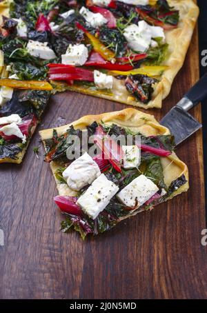 Pane piatto tradizionale italiano con verdure al mangelo e formaggio feta servito da vicino su un moderno asse di legno Foto Stock