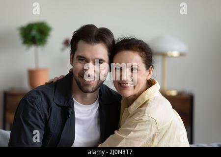 Mamma felice matura abbracciando un bel figlio cresciuto a casa Foto Stock