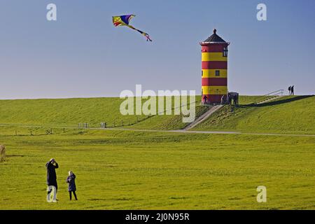 La ragazza lascia volare un aquilone di fronte al faro di Pilsum, Pilsum, Frisia orientale, Germania, Europa Foto Stock