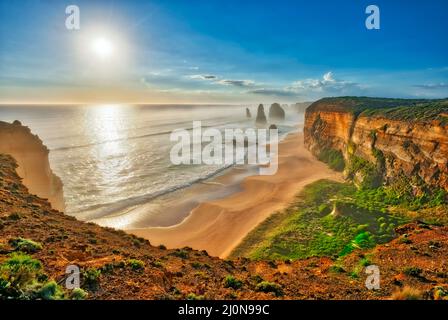 Il sole tramonta dietro gli splendidi 12 Apostoli, Shipwreck Coast, Great Ocean Road, Victoria, Australia Foto Stock