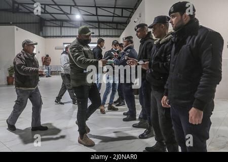 Beit Hanoun, territori palestinesi. 20th Mar 2022. Gli ufficiali di polizia controllano i documenti dei lavoratori palestinesi all'incrocio di Erez mentre lasciano Beit Hanoun nella striscia settentrionale di Gaza, per andare a lavorare all'interno di Israele. Israele si prepara a rilasciare 2.000 permessi di lavoro ai palestinesi che vivono a Gaza, portando il numero totale di lavoratori da parte israeliana a 12.000. Credit: Mohammed Talatene/dpa/Alamy Live News Foto Stock