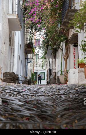 Una ragazza che cammina su una strada Cadaques bella città sullo sfondo in Costa Brava Catalogna Foto Stock