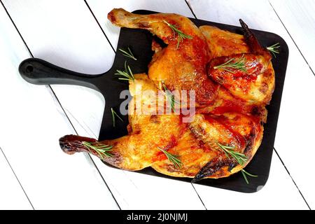 Pollo arrosto intero con spezie, salsa e pelle croccante sul tagliere. Concetto di cibo per le vacanze. Messa a fuoco selettiva. Vista dall'alto. Primo piano. Foto Stock