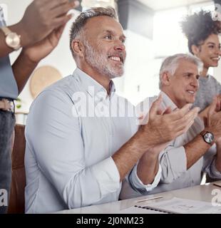 Il profitto potenziato merita un grande coraggio. Scatto di un gruppo di uomini d'affari che si aggrappano durante una conferenza in un ufficio moderno. Foto Stock