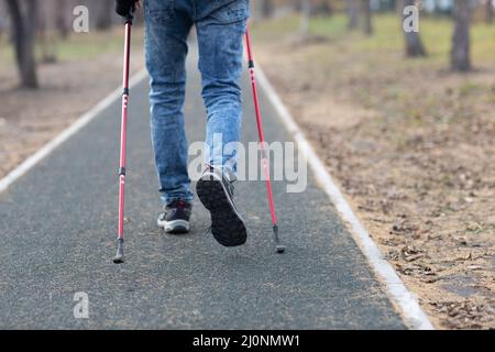 Il giovane cammina con bastoni da passeggio scandinavi. Stile di vita sano. Foto Stock