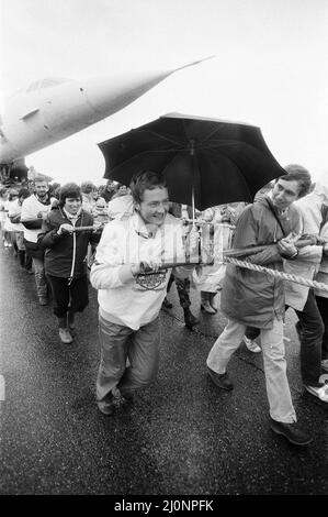 Centinaia di persone sono state addensate da forti piogge mentre hanno tirato la Concorde intorno a un campo aereo alla fine di una corda. Stavano facendo un tentativo di rompere i record per raccogliere soldi per i bambini disabili fisici e mentali. L'idea è venuta dal Wickford Rotary Club. Il piano è uno degli aerei statici in mostra al Duxford, Imperial War Museum. 9th settembre 1983. Foto Stock