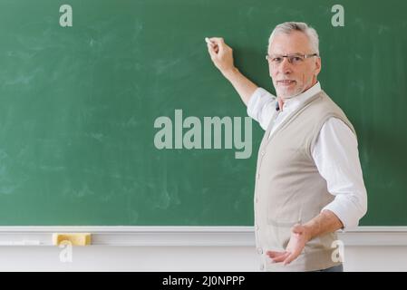 Professore maschile senior che spiega scrivere lavagna verde . Alta qualità e risoluzione bellissimo concetto di foto Foto Stock