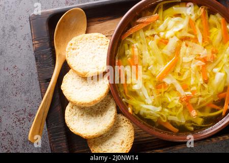 Zuppa vegetariana di julienne di verdure servita con toast primo piano in una ciotola su un vassoio di legno vista dall'alto orizzontale Foto Stock