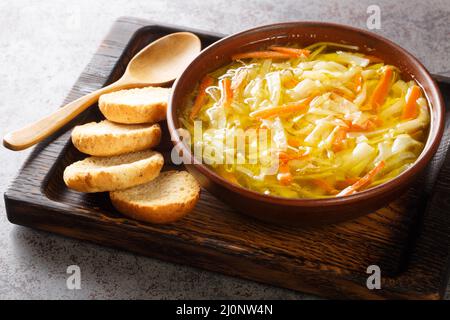 Zuppa vegetariana di julienne di verdure servita con toast primo piano in una ciotola su un vassoio di legno orizzontale Foto Stock