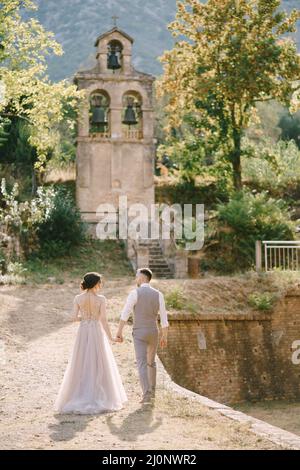 Sposi e sposi andare ad una piccola cappella nel giardino di una vecchia villa Foto Stock