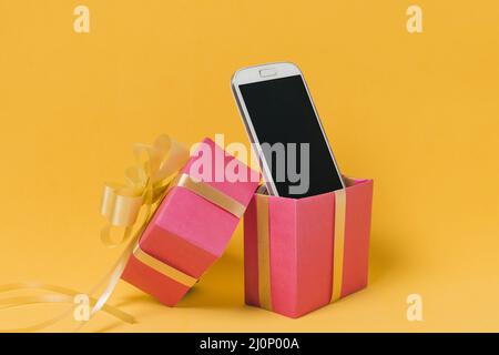 Telefono cellulare con schermo bianco scatola regalo rosa . Alta qualità e risoluzione bellissimo concetto di foto Foto Stock