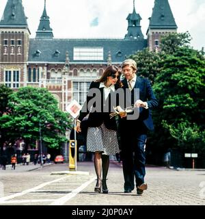 Vintage Amsterdam 1970s, elegante coppia di turisti di mezza età che passeggiando di fronte al Rijksmuseum, Olanda, Paesi Bassi, Europa, Foto Stock