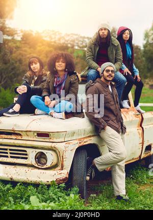 La cosa migliore dei ricordi è renderli. Ritratto di un gruppo di amici posto intorno a un vecchio camion in un campo. Foto Stock