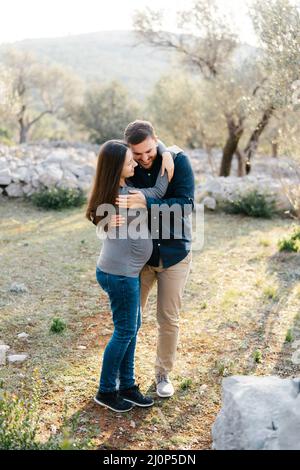 Uomo che abbraccia una donna incinta nel parco Foto Stock