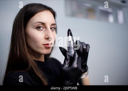 Il cosmetologo controlla l'apparecchiatura prima di fare la procedura di microblading Lips tatuaggio Foto Stock