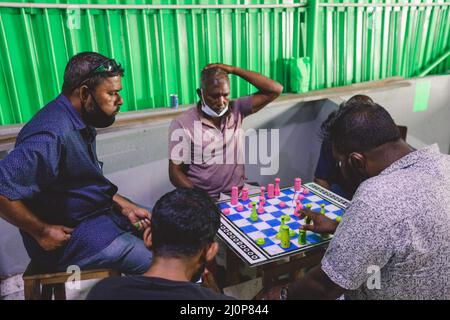 Gruppo di Maldivian locale uomo che gioca a scacchi vicino al muro verde sulla strada di Male City Foto Stock