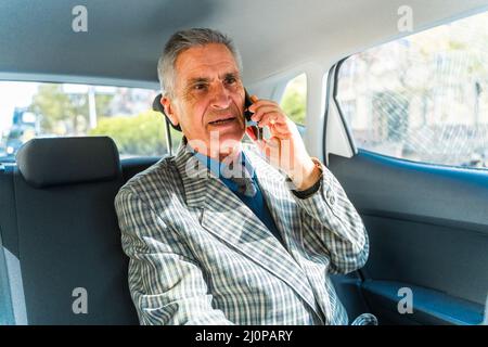 L'uomo d'affari anziano e bello sta avendo una chiamata dai suoi soci Foto Stock