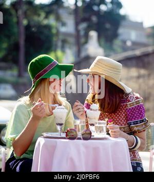 Vintage Roma anni '1970, 2 donne con cappello che chiacchiera e mangiano gelati, faccia l'una con l'altra, terrazza pasticceria Rosati, Piazza di Populo, Italia, Europa, Foto Stock