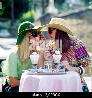 Roma vintage anni '1970, 2 donne con cappelli e occhiali da sole che chiacchierano mentre mangiavano gelati, l'una con l'altra, terrazza pasticceria Rosati, Piazza di Populo, Italia, Europa, Foto Stock