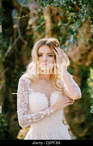 Sposa in un abito bianco si erge nel parco. Verticale Foto Stock