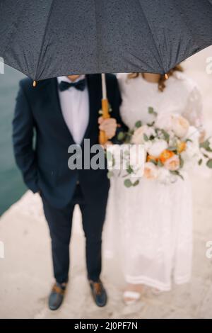 Gocce di pioggia su un ombrello sopra la sposa e lo sposo. Sfocatura. Primo piano Foto Stock