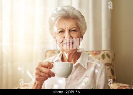 Alcune tradizioni non invecchiano mai, come il mio tè pomeridiano. Ritratto di una donna anziana felice godendo una tazza di tè a casa. Foto Stock