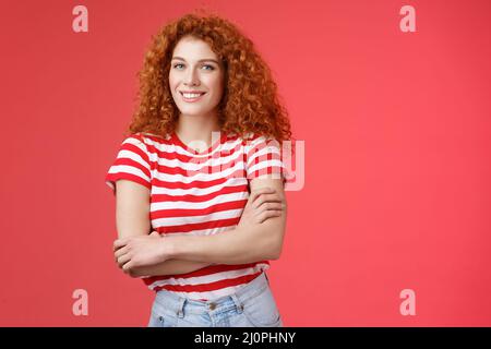 Fiducioso tenero silly redhead bella ragazza ricci-capelli croce braccia corpo sorridente ampiamente felice divertito allegramente godersi la guerra Foto Stock