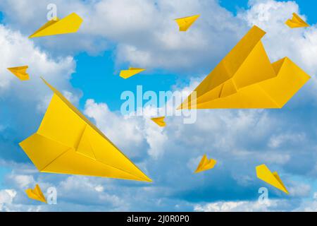 Piani di carta gialla che volano in un cielo nuvoloso Foto Stock