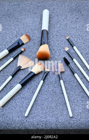 closeup il mazzo bianco marrone makeup kit spazzolare su sfondo grigio marrone fuori fuoco. Foto Stock
