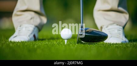 Golf Ball on the Tee nel campo di erba Turf, golfista che colpisce da Golf Club driver. Primo piano White Golf Shoes Foto Stock