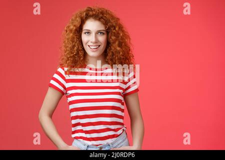 Sassy fiducioso cheeky buona-osservare redhead ricci-capelli donna tenere le mani tasche sorridenti audaci assertivi motivati hanno perfettamente Foto Stock