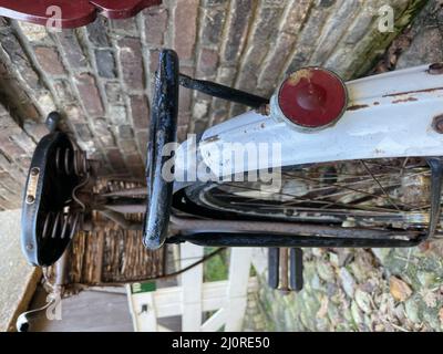 Colpo verticale della vecchia bicicletta appoggiata contro la parete di mattone Foto Stock