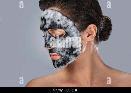 Donna con maschera bolla foglio sul suo viso Foto Stock