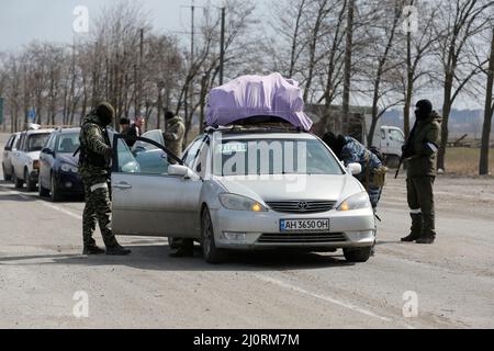 I membri di servizio delle truppe pro-russe controllano le automobili, mentre i residenti locali lasciano la città portuale meridionale assediata di Mariupol, Ucraina 20 marzo 2022. REUTERS/Alexander Ermochenko