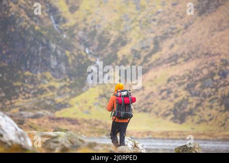 Vista posteriore di escursionista isolato femmina a piedi con zaino in Snowdonia National Park, Galles del Nord, Regno Unito, in vacanza selvaggia campeggio avventura. Foto Stock