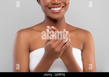 Primo piano Shot di Donna Nera sorridente usando crema idratante per le mani Foto Stock