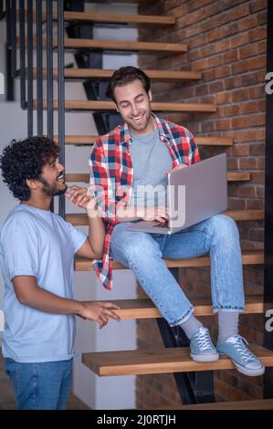 Uomo contento che guarda il suo ragazzo seduto sui gradini Foto Stock