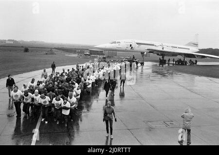 Centinaia di persone sono state addensate da forti piogge mentre hanno tirato la Concorde intorno a un campo aereo alla fine di una corda. Stavano facendo un tentativo di rompere i record per raccogliere soldi per i bambini disabili fisici e mentali. L'idea è venuta dal Wickford Rotary Club. Il piano è uno degli aerei statici in mostra al Duxford, Imperial War Museum. 9th settembre 1983. Foto Stock