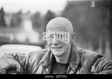 John Hurt filma vicino Lambourn, West Berkshire.He sta filmando, giocando la parte di Bob Champion, nel film Champions. Bob Champion ha combattuto contro il cancro per vincere il 1981 Grand National sul cavallo Aldaniti. E questo è il bioptico. Vedi altre cornici in questo set di 3 cornici, di John Hurt, apparendo calvo come le sue scene di trattamento sullo schermo sono girate. Foto scattata il 9th aprile 1983 Foto Stock