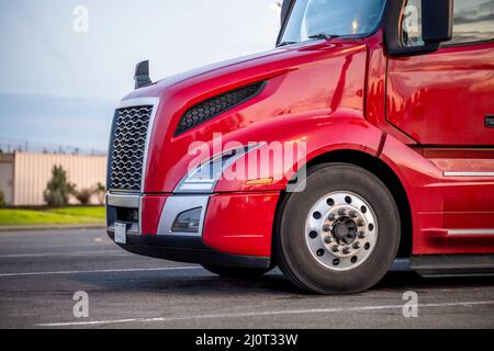 Profilo del trattore semi-camion professionale per il trasporto di merci di grado industriale con cofano rosso brillante e brillante in piedi sul parcheggio al crepuscolo w Foto Stock