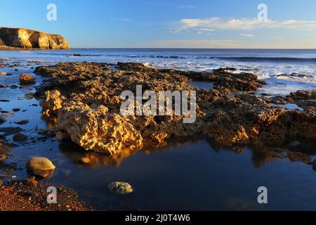 Luce del mattino a Blast Beach con rocce calcaree di magnesio nel primo piano, Seaham, County Durham, Inghilterra, Regno Unito. Foto Stock