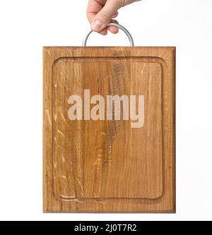 Le mani femminili tengono il tagliere di legno rettangolare marrone vuoto su sfondo bianco Foto Stock