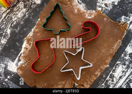 Taglierine per biscotti natalizi in pasta di Gingerbread sulla superficie infarinata Foto Stock