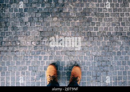 Piedi maschi in stivali marroni si levano in piedi sul ciottoli. Primo piano Foto Stock