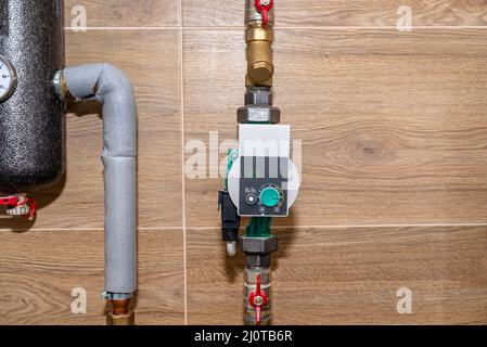 La pompa di circolazione dell'acqua per il riscaldamento a pavimento in un moderno locale caldaia a gas rivestito di piastrelle in ceramica, mostra un valore di 25 watt. Foto Stock