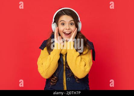 stupito bambino in cappello ascoltare musica in cuffie, tecnologia Foto Stock